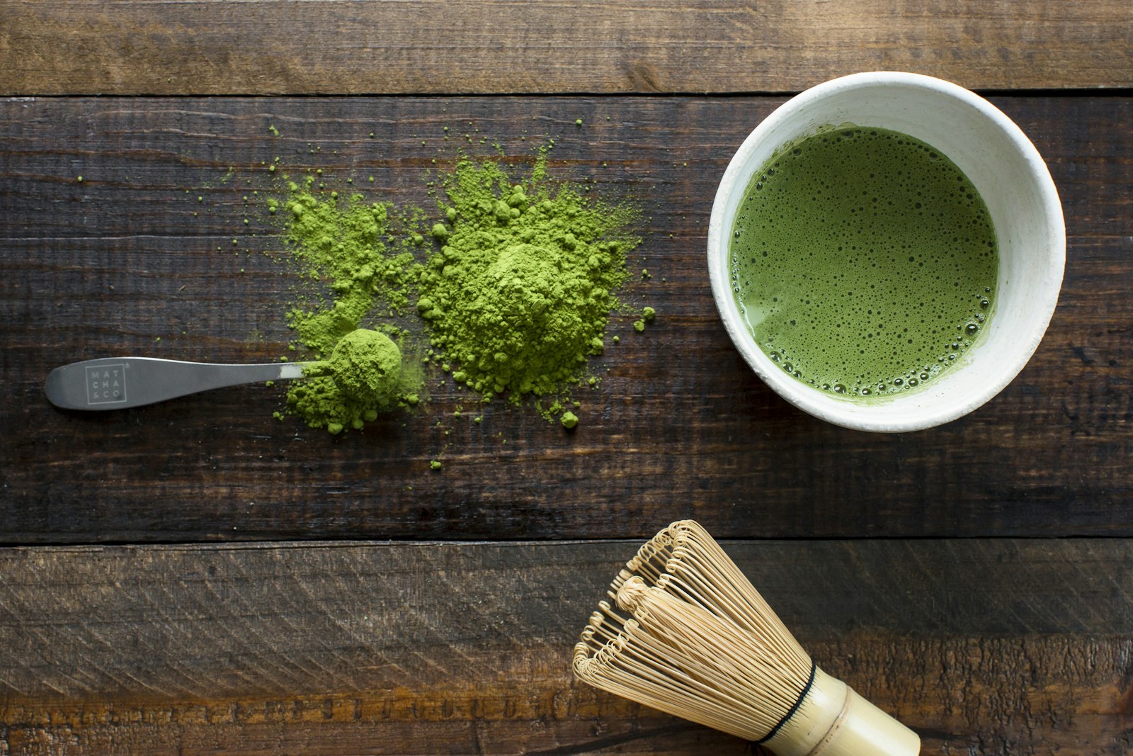 Vivid green ceremonial matcha powder beside a bamboo whisk and bowl